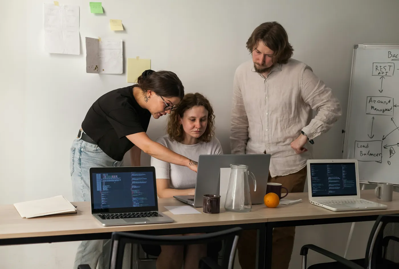 Three colleagues reviewing work together at a table with laptops